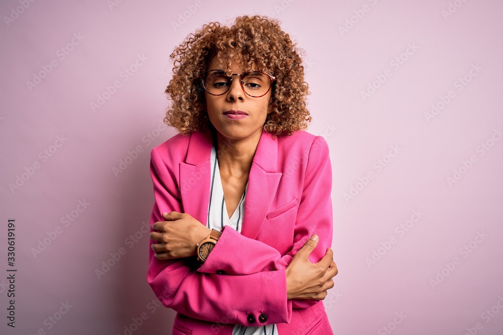 Young african american businesswoman wearing glasses standing over pink background shaking and freezing for winter cold with sad and shock expression on face