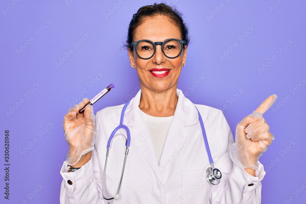 Middle age senior female doctor holding medice blood sample of coronavirus infection disease very happy pointing with hand and finger to the side Middle age senior female doctor holding medice blood sample of coronavirus infection disease very happy pointing with hand and finger to the side