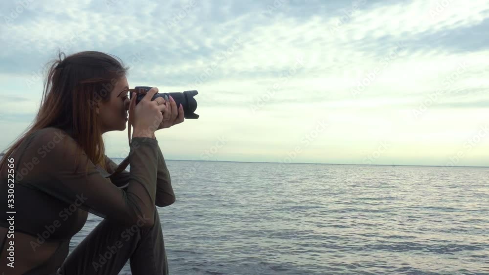 Girl-photographer sits on a stone shore and takes pictures. Natural landscape. Cumulus clouds. Girl-photographer sits on a stone shore and takes pictures. Natural landscape. Cumulus clouds.