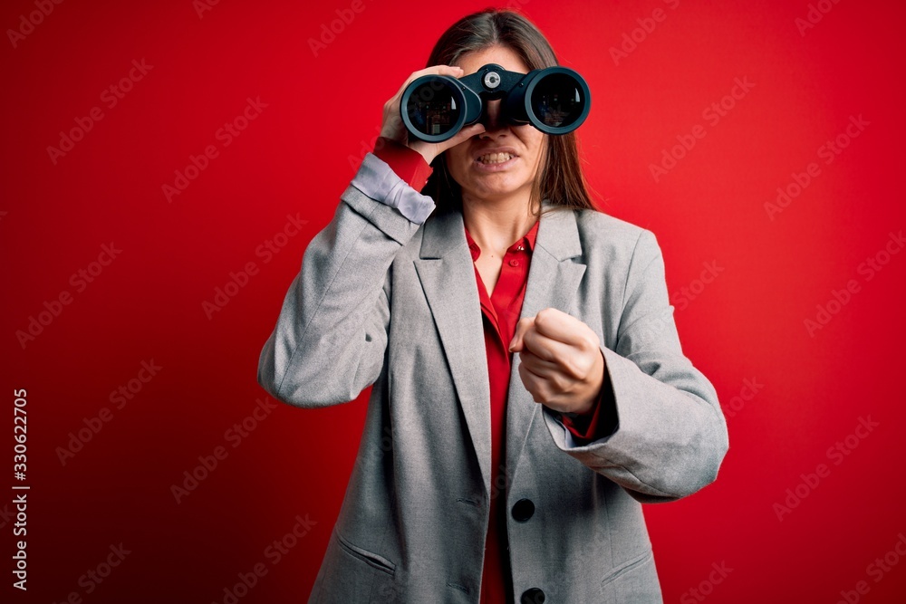 Young beautiful woman with blue eyes using binoculars over isolated red background annoyed and frustrated shouting with anger, crazy and yelling with raised hand, anger concept Young beautiful woman with blue eyes using binoculars over isolated red background annoyed and frustrated shouting with anger, crazy and yelling with raised hand, anger concept