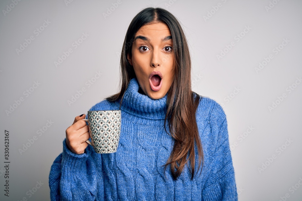 Young beautiful brunette woman drinking cup of coffee over isolated white background scared in shock with a surprise face, afraid and excited with fear expression Young beautiful brunette woman drinking cup of coffee over isolated white background scared in shock with a surprise face, afraid and excited with fear expression