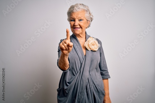 Senior beautiful grey-haired woman wearing casual dress standing over white background pointing finger up with successful idea. Exited and happy. Number one.