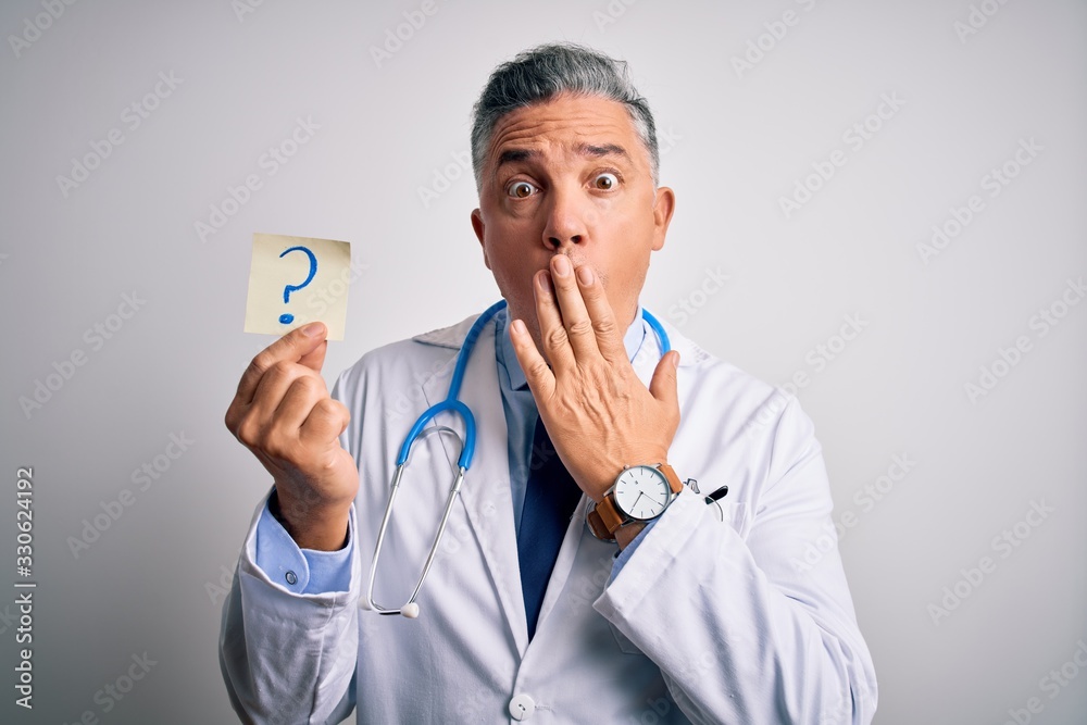 Middle age handsome grey-haired doctor man holding paper with question mark cover mouth with hand shocked with shame for mistake, expression of fear, scared in silence, secret concept Middle age handsome grey-haired doctor man holding paper with question mark cover mouth with hand shocked with shame for mistake, expression of fear, scared in silence, secret concept