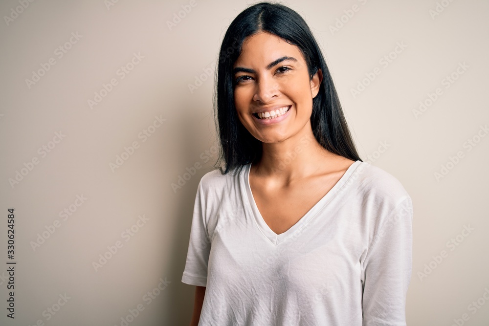 Young beautiful hispanic woman wearing casual white t-shirt over isolated background with a happy and cool smile on face. Lucky person. Young beautiful hispanic woman wearing casual white t-shirt over isolated background with a happy and cool smile on face. Lucky person.