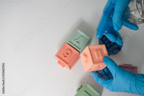 Hands in nitrile gloves are cleaning and disinfecting toys