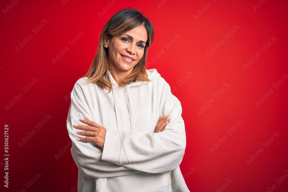 Middle age beautiful sportswoman wearing casual sweatshirt over isolated red background happy face smiling with crossed arms looking at the camera. Positive person. Middle age beautiful sportswoman wearing casual sweatshirt over isolated red background happy face smiling with crossed arms looking at the camera. Positive person.