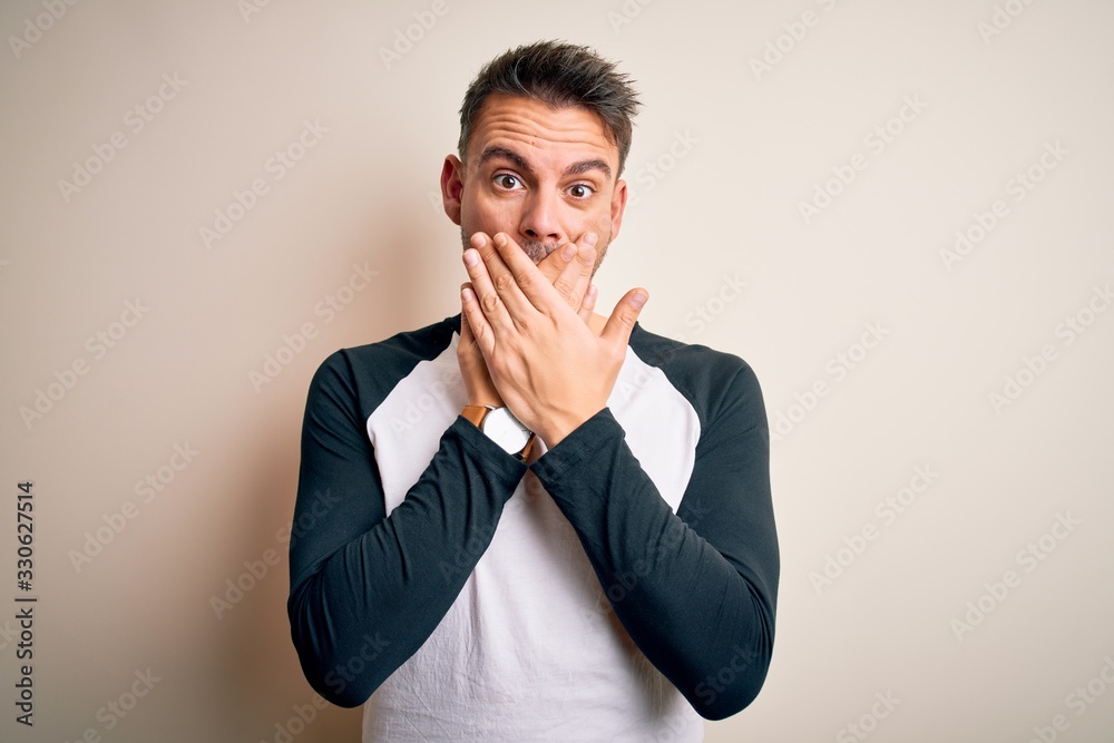 Young handsome man wearing casual t-shirt standing over isolated white background shocked covering mouth with hands for mistake. Secret concept. Young handsome man wearing casual t-shirt standing over isolated white background shocked covering mouth with hands for mistake. Secret concept.