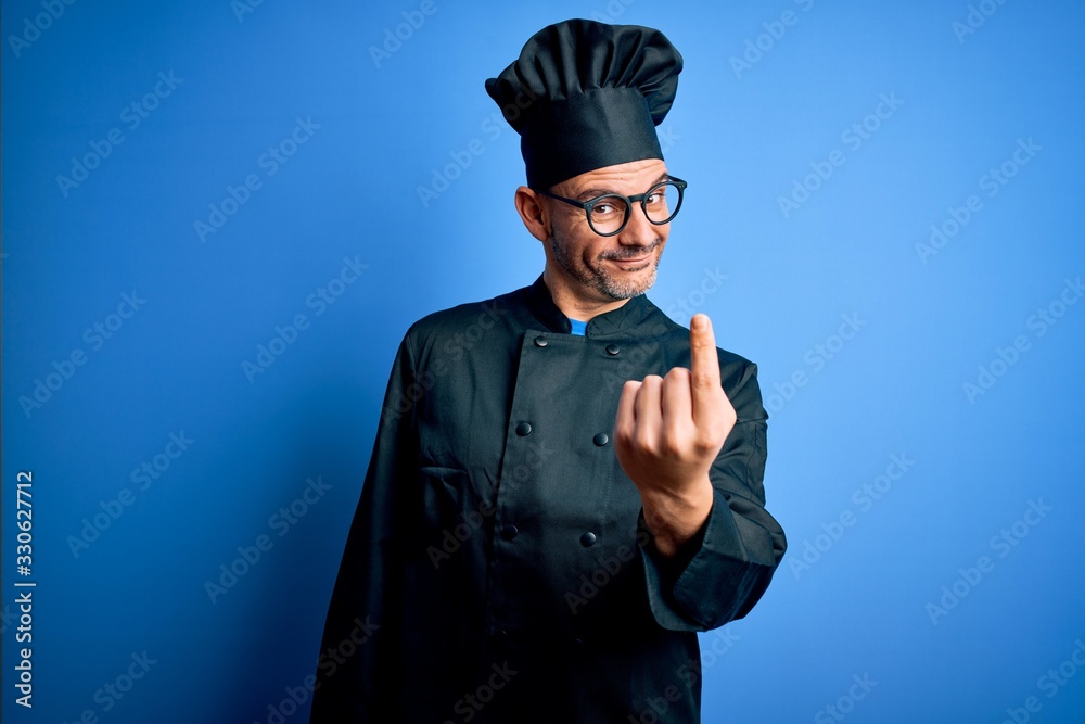 Young handsome chef man wearing cooker uniform and hat over isolated blue background Beckoning come here gesture with hand inviting welcoming happy and smiling Young handsome chef man wearing cooker uniform and hat over isolated blue background Beckoning come here gesture with hand inviting welcoming happy and smiling