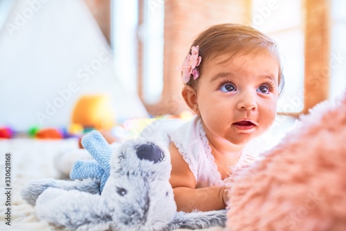 Beautiful infant happy at kindergarten around colorful toys lying on blacket photo