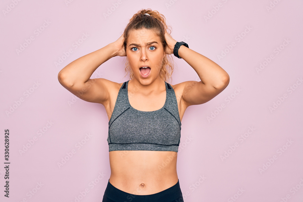 Young beautiful blonde sportswoman with blue eyes doing exercise wearing sportswear Crazy and scared with hands on head, afraid and surprised of shock with open mouth