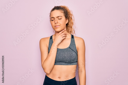 Young beautiful blonde sportswoman with blue eyes doing exercise wearing sportswear Touching painful neck, sore throat for flu, clod and infection © Krakenimages.com