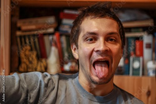 young attractive man looking at the camera and showing tongue. A guy sitting at library.