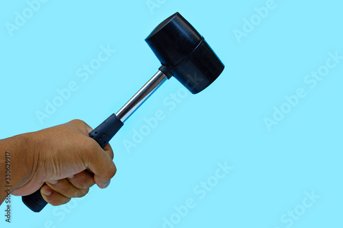 Man's hand holding hammer on blue background.
