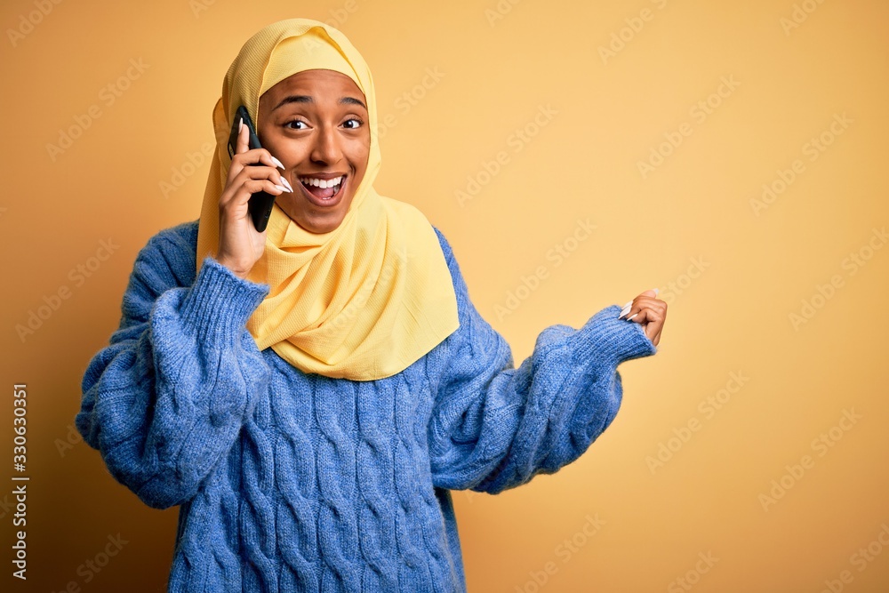 African American woman wearing muslim hijab having conversation talking on smartphone screaming proud and celebrating victory and success very excited, cheering emotion African American woman wearing muslim hijab having conversation talking on smartphone screaming proud and celebrating victory and success very excited, cheering emotion