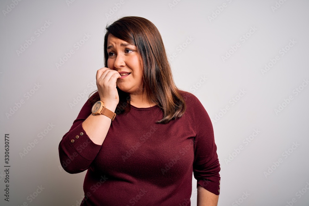 Beautiful brunette plus size woman wearing casual sweater over isolated white background looking stressed and nervous with hands on mouth biting nails. Anxiety problem. Beautiful brunette plus size woman wearing casual sweater over isolated white background looking stressed and nervous with hands on mouth biting nails. Anxiety problem.