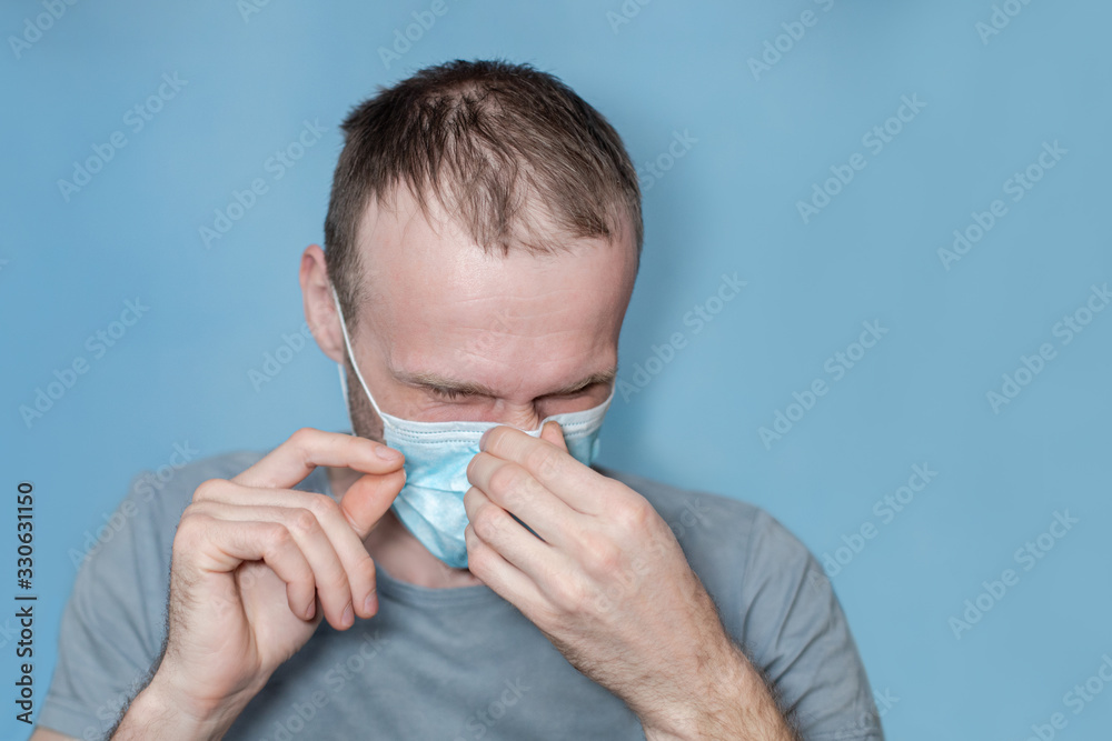 man adjusts protective mask on face. man holds nose with hands. risk of infection from touching face. hild with flu, influenza or cold protected from viruses among patients with coronavirus man adjusts protective mask on face. man holds nose with hands. risk of infection from touching face. hild with flu, influenza or cold protected from viruses among patients with coronavirus