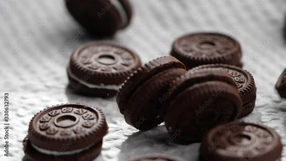 Chocolate cookies and cream falling into white paper in slow motion Chocolate cookies and cream falling into white paper in slow motion