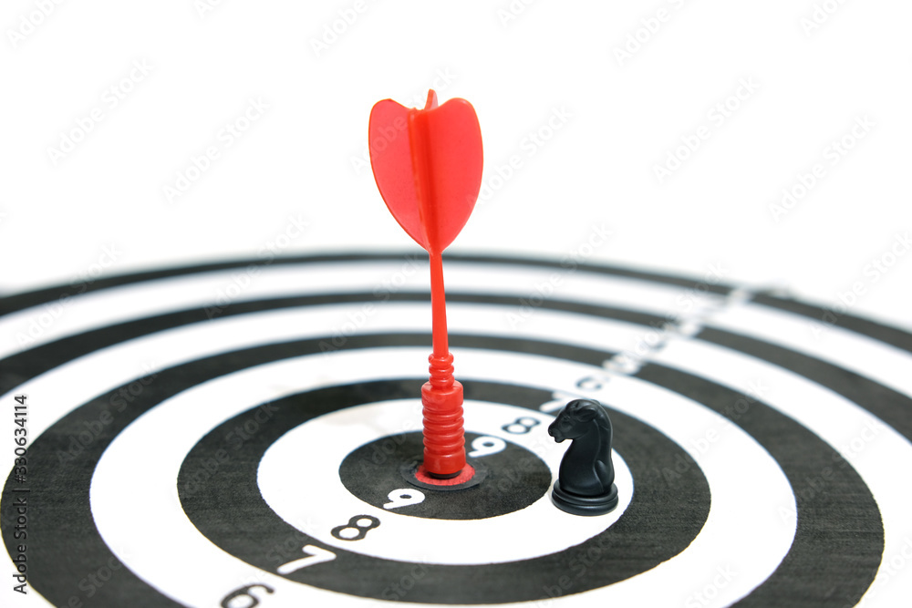 Conceptual picture of success and victory - red arrow stuck right in the middle of the target board with chess horse piece Conceptual picture of success and victory - red arrow stuck right in the middle of the target board with chess horse piece
