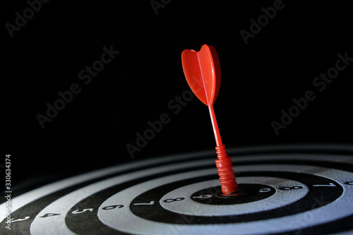 Conceptual photo of business strategy / accuracy - a red arrow that sticks directly in the center of the target dartboard