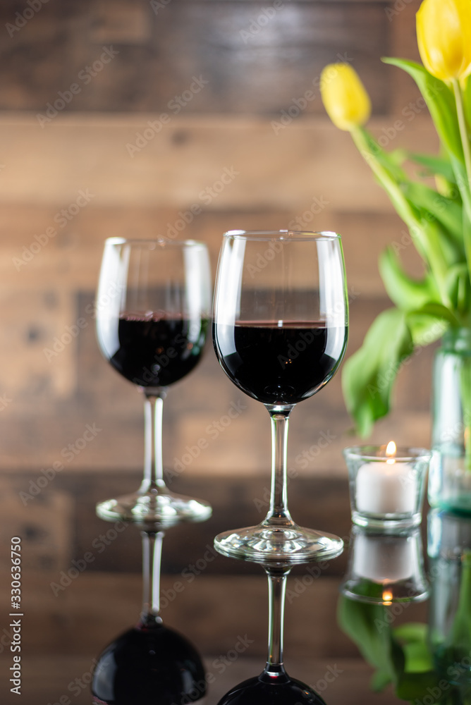 Two glasses of red wine on a table with candles and flowers Two glasses of red wine on a table with candles and flowers