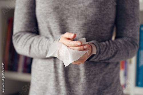 Close up on midsection of young caucasian woman hands wiping using white alcohol tissue cleaning napkin disinfection from virus and bacteria in day at home or office front view