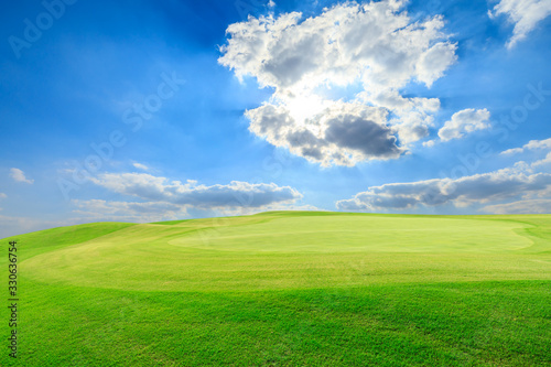 Green grass field and blue sky with white clouds.