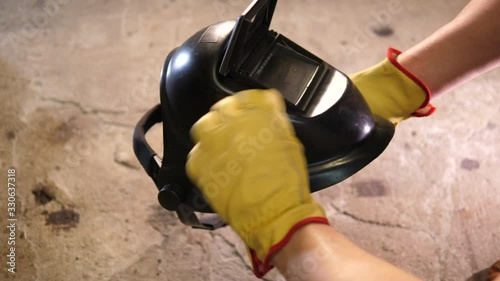 Welder inspecting and wears black Helmet with protective glass. Wearing yellow gloves. POV.