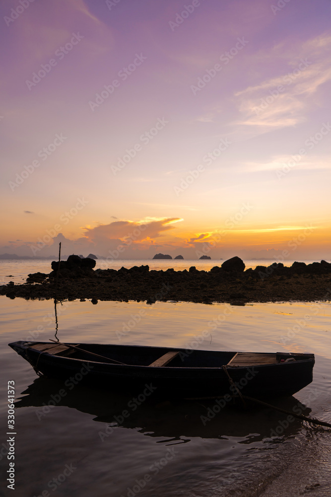 Wooden boat off the coast of a tropical island. Evening, sunset in the ocean. Tropical landscape. Light waves rock the boat