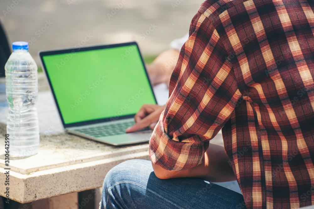 Asian student Using laptop in college.Person back view of man typing on notebook,bottle of water placed on table.Technology Concept. Asian student Using laptop in college.Person back view of man typing on notebook,bottle of water placed on table.Technology Concept.