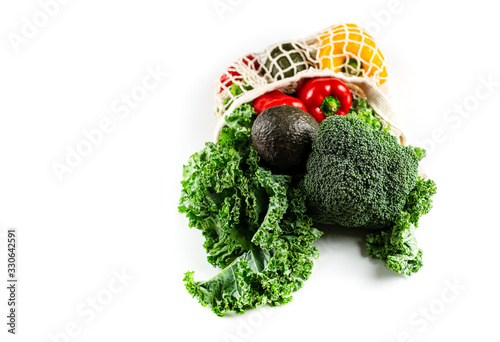 Eco friendly mesh bag with organic vegetables: Kale salad, broccoli, avocado, bell peppers on white background. Flat lay, top view. Zero waste concept. Healthy clean eating diet and detox. Copy space