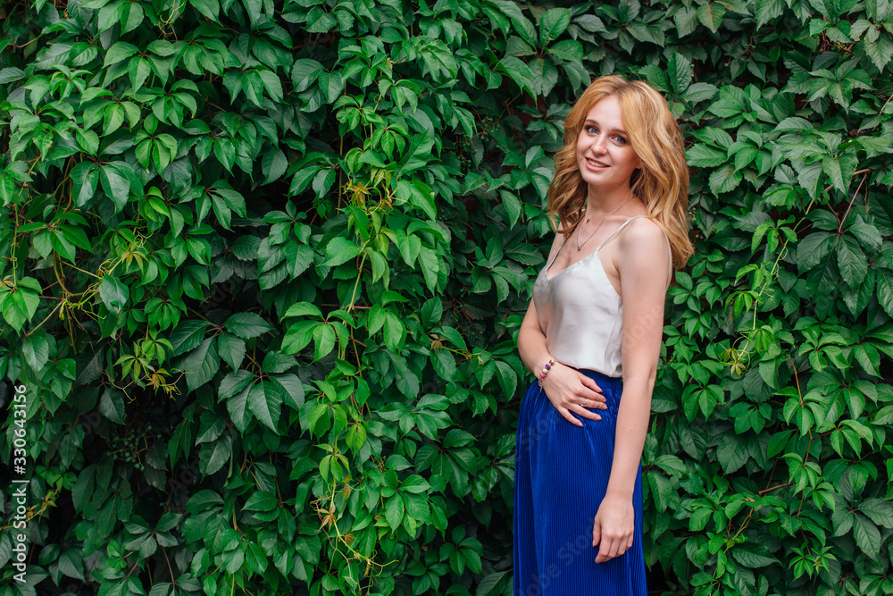 Portrait of a young beautiful woman, standing next to the wall of wild grape leaves. Portrait of a young beautiful woman, standing next to the wall of wild grape leaves.