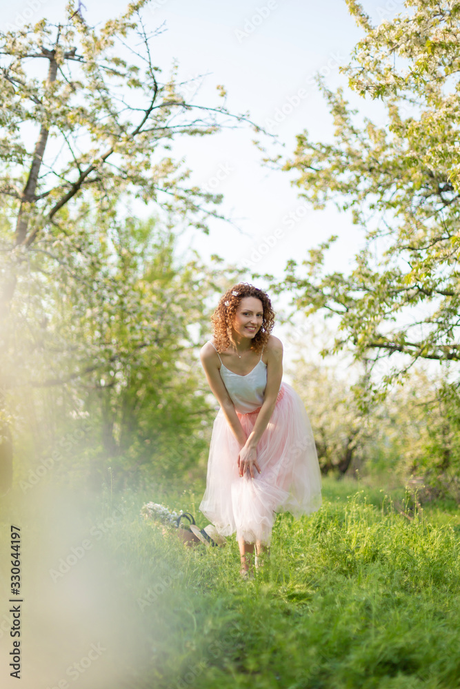 Young attractive girl walks in spring green park enjoying flowering nature Young attractive girl walks in spring green park enjoying flowering nature