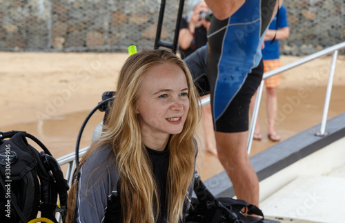 young blonde diver girl in outfit on background of equipment sitting in boat
