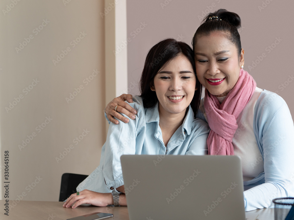 Happy asian family Mother and daughter hugging using laptop computer together on table in home. Technology Communication and lifestyle Happy asian family Mother and daughter hugging using laptop computer together on table in home. Technology Communication and lifestyle