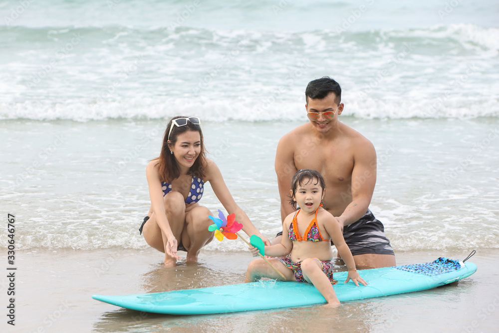 Obraz premium Young asian family and daughters who wearing swimwear are playing sand on the beach during happy and loving times with smiling face on holiday vacation.