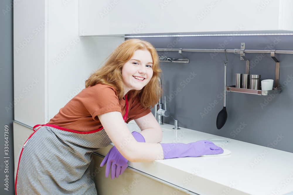 teenager girl in purple rubber gloves washes dishes in kitchen teenager girl in purple rubber gloves washes dishes in kitchen