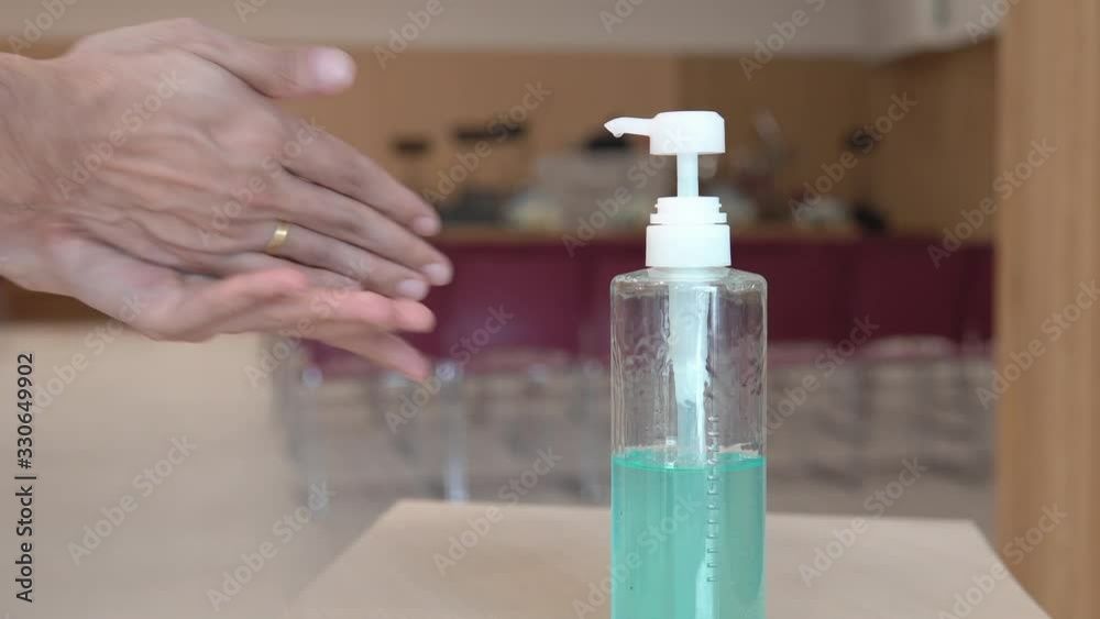 Closeup, Hands of a man press pump bottle of 60% alcohol-based hand sanitizer gel to clean his hand to protect from infection of virus outbreak, covid-19 pandemic at entrance of conference room.
