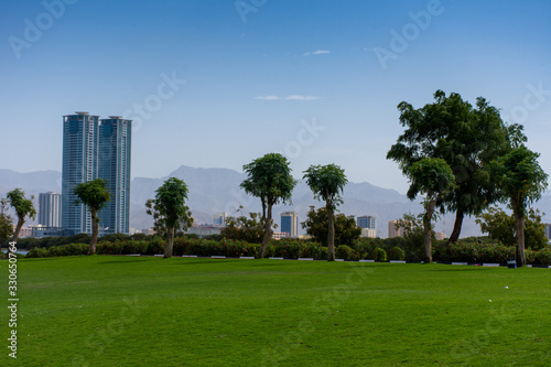 Ras al Khaimah, United Arab Emirates Corniche with green grass picnic and family area, looking towards the mountains on a sunny day.