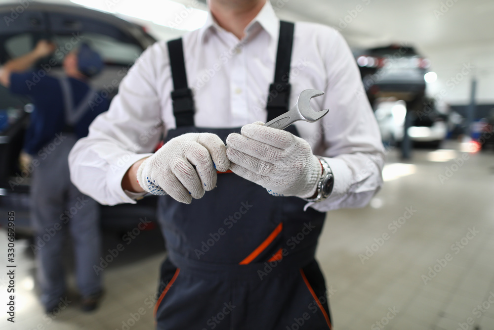 Fototapeta premium Close-up view of male specialist showing mechanical tool for fixing automobiles. Service station and car maintenance concept. Special professional equipment for garage worker
