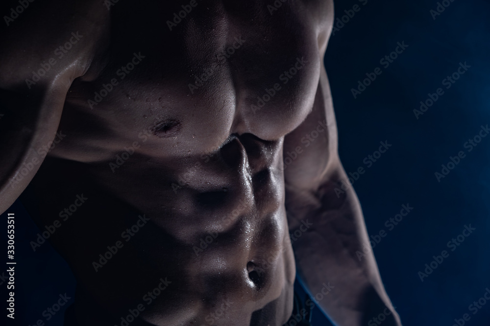 Muscular man showing muscles isolated on the black background. Concept of healthy lifestyle 