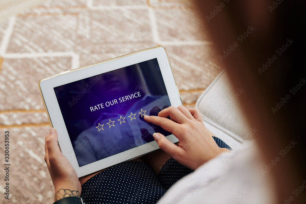 Woman rating service and leaving feedback via application on tablet computer Woman rating service and leaving feedback via application on tablet computer