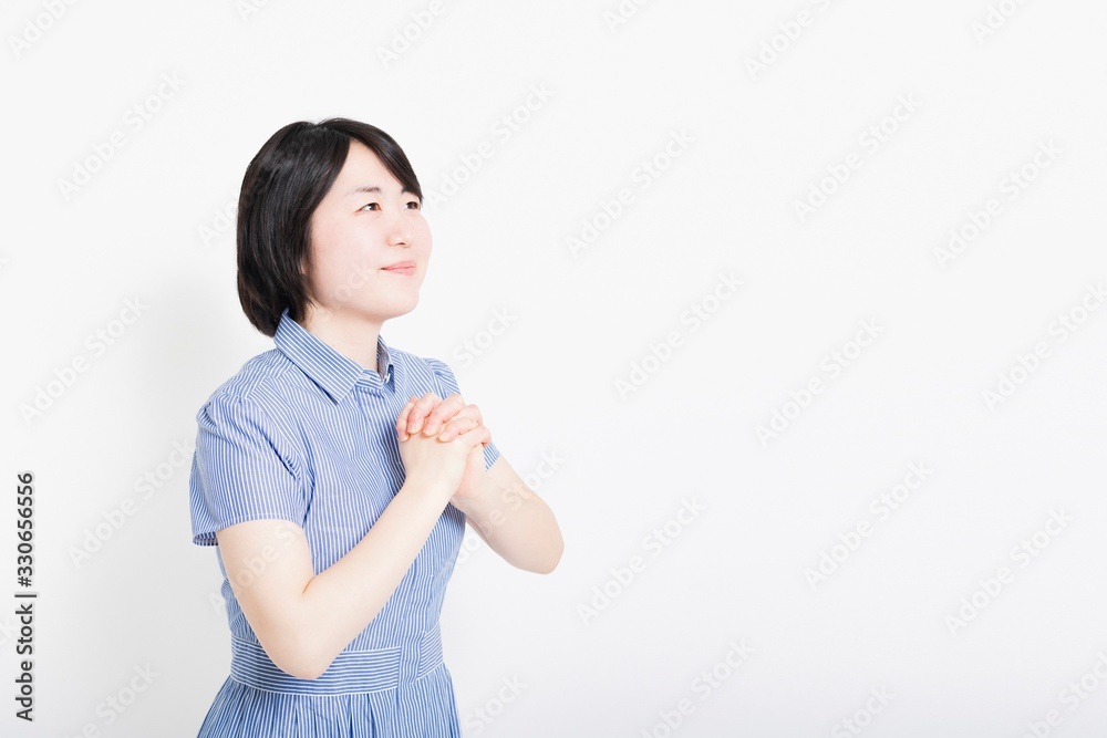 胸の前で手を合わせてお願いするワンピースを着た女性