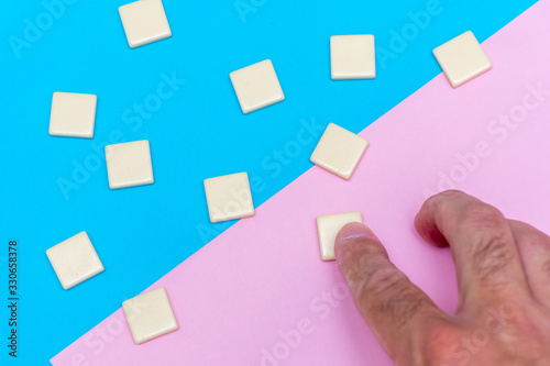 Blue and pink background with scattered blank word tile blocks with hand for concept of growth, goal setting, progress and achievement in business or education.