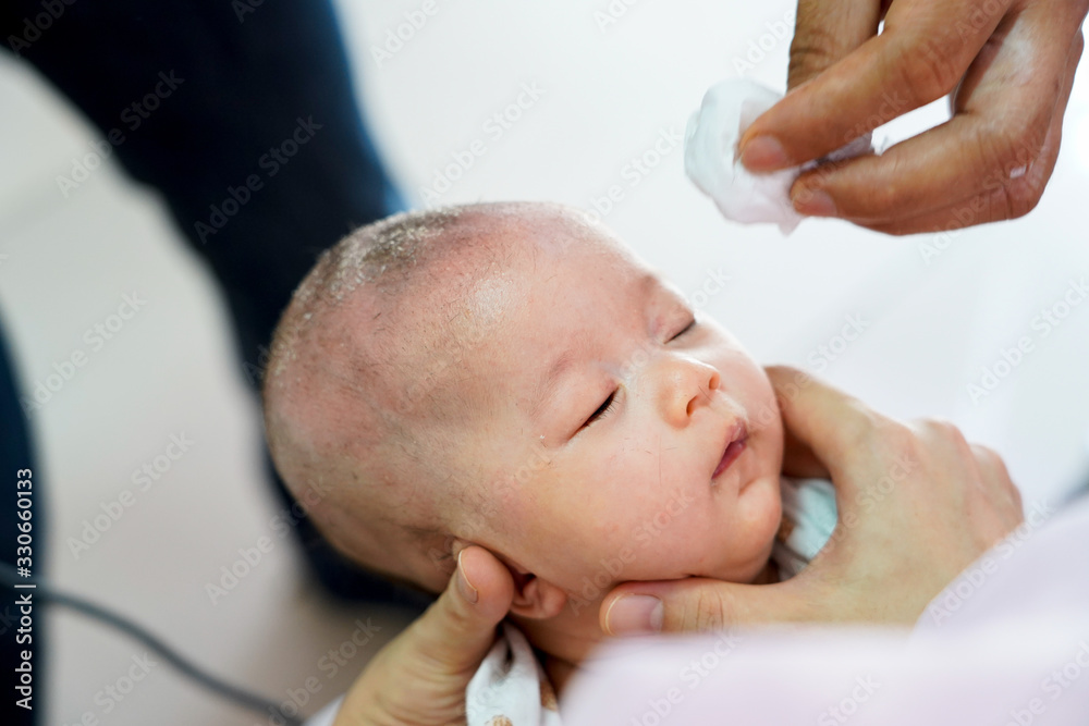 Baby one month old is shaved the hair in barber shop. Thai traditional