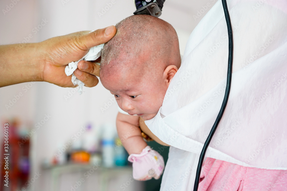 Baby one month old is shaved the hair in barber shop. Thai traditional