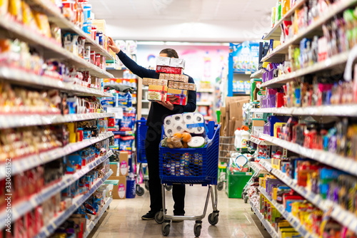 Fototapeta Full shopping cart, customer is stocking vital needs because of global chaos