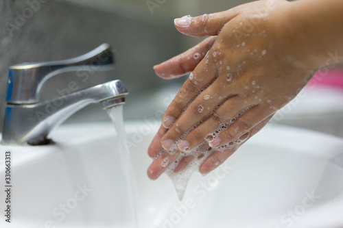 close up adult woman washing and rubbing hand while opening faucet to cleaning soap for protection and prevent virus and bacteria concept