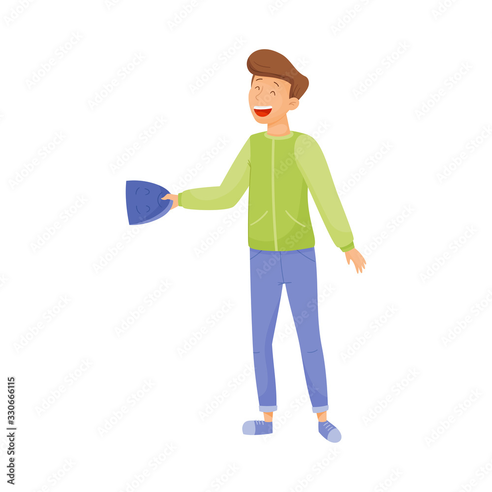 Young Smiling Man Standing and Holding Mask with Sad Face in His Hands