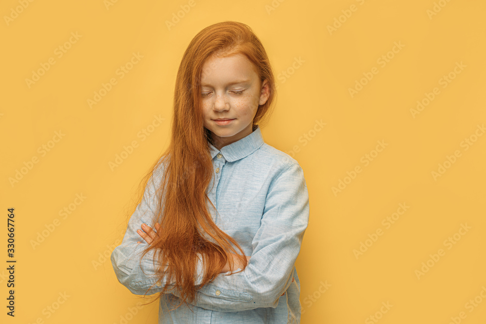 portrait of calm caucasian red haired girl with closed eyes isolated over yellow background. natural red hair, freckles, beauty concept
