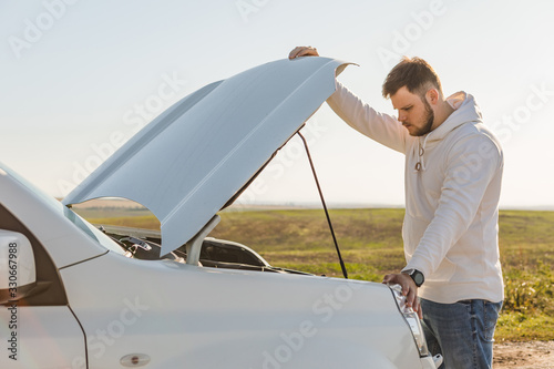 man standing near car with opened hood on sunset